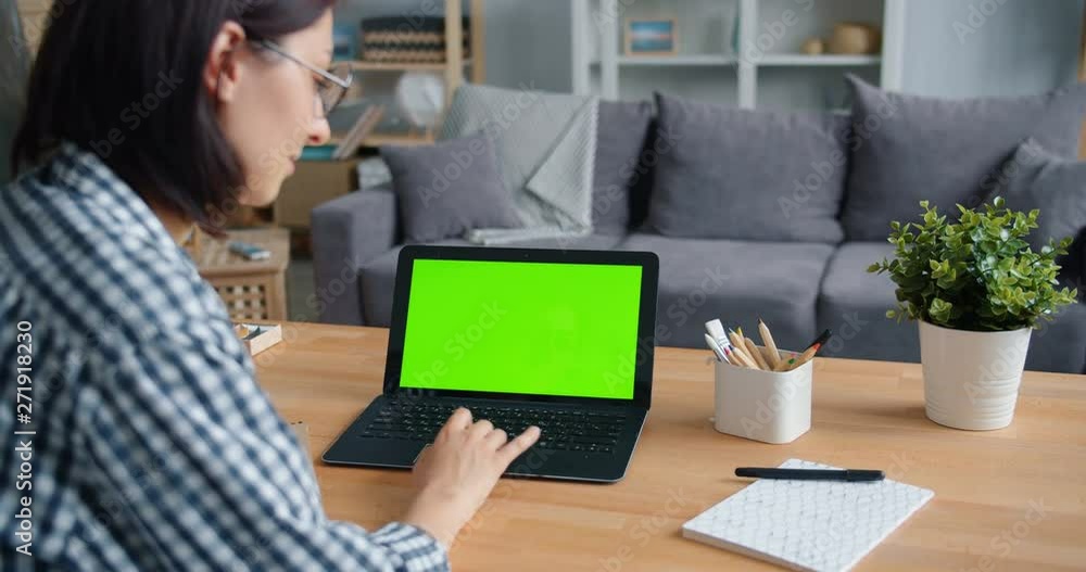 Slow motion of person young woman using laptop computer with green mock-up screen at home touching touchpad sitting at desk in apartment. Media and internet concept. Slow motion of person young woman using laptop computer with green mock-up screen at home touching touchpad sitting at desk in apartment. Media and internet concept.