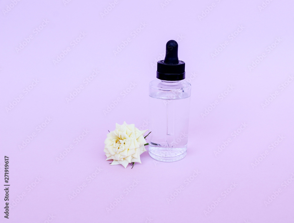 Glass bottle with pipette with oil or serum, with white rose flower on delicate background. Concept: organic bio cosmetics, vegetable oils, serum collagen, skin care Glass bottle with pipette with oil or serum, with white rose flower on delicate background. Concept: organic bio cosmetics, vegetable oils, serum collagen, skin care