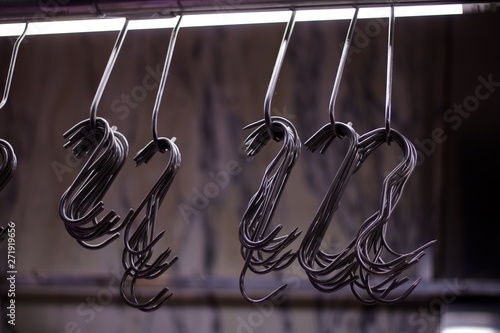 Row of metal butcher's hooks against soft grey background photo