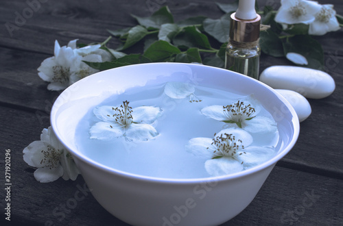 Essential aromatic oil with jasmine on wooden background. © Maryna Osadcha