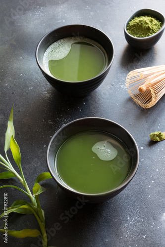 Organic two green matcha tea in bowl on black table.
