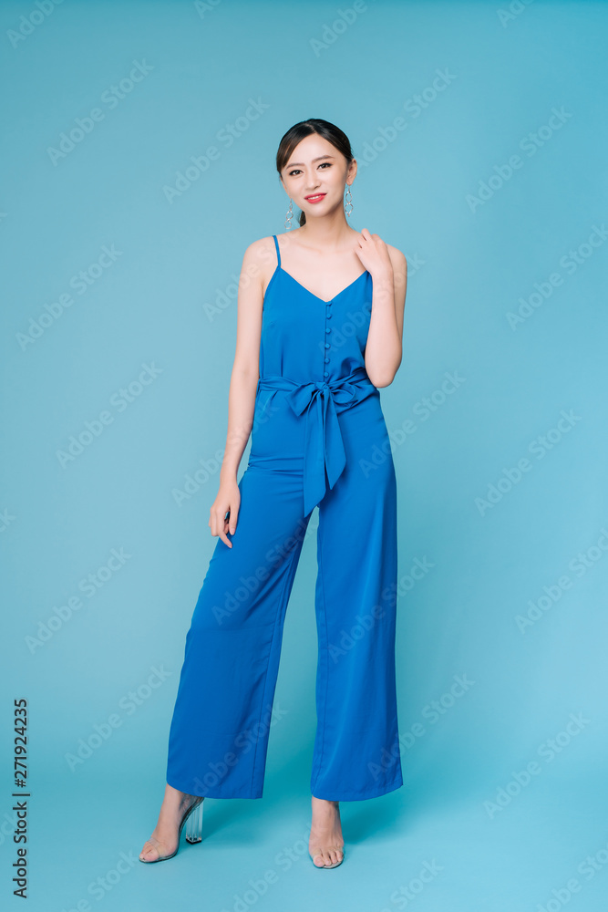 Young beautiful woman posing in new casual blue fashion costume dress with pants full body on blue background Young beautiful woman posing in new casual blue fashion costume dress with pants full body on blue background