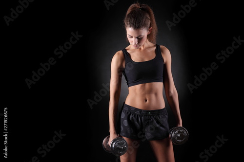 Beautiful fitness woman lifting dumbbells