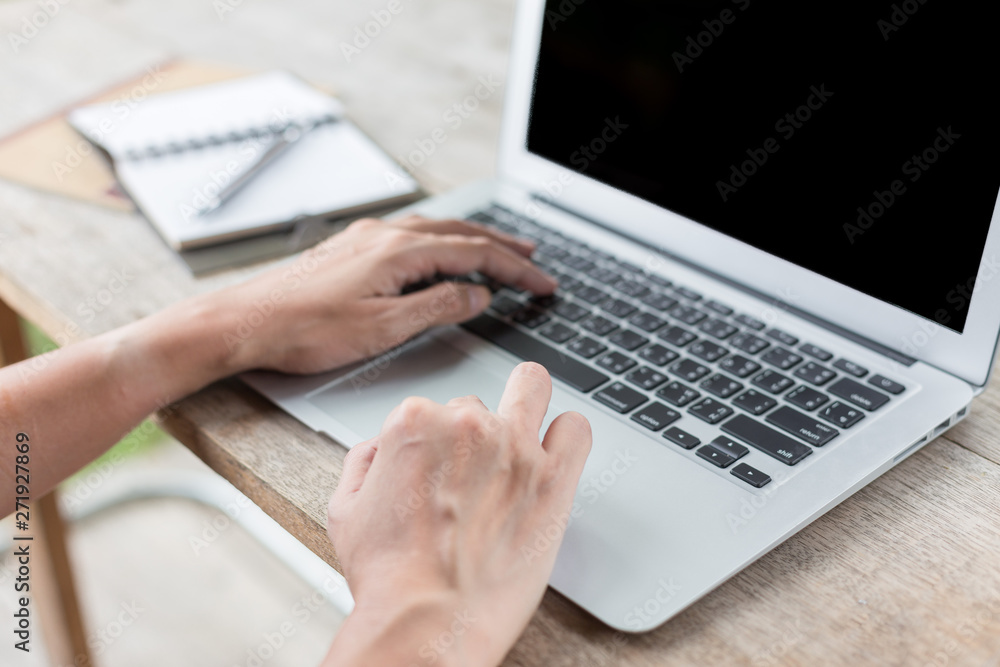 Fototapeta premium Woman hand using laptops and has a notebook and a pen with warm light