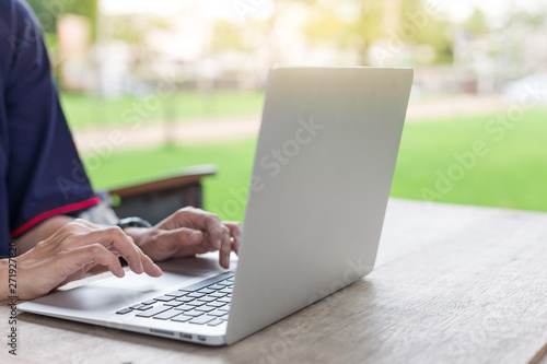 Woman hand using laptops and has a notebook and a pen with warm light