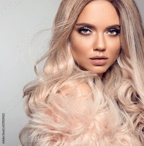 Ombre blond hairstyle. Beauty fashion blonde portrait. Sexy woman wears in  pink fur coat. Beautiful girl model with makeup, long healthy hair style  posing isolated on studio grey background. Stock Photo