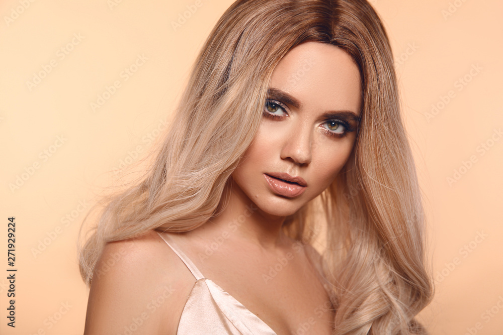 Fototapeta premium Ombre blond hairstyle. Beauty fashion blonde woman portrait. Beautiful girl model with makeup, long healthy hair style posing isolated on studio beige background.