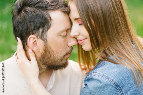 the girl and the guy are sitting on the grass near the blossoming lilac bush in the spring in the park and both are denying themselves. concept of a relaxing holiday in a weekend in nature