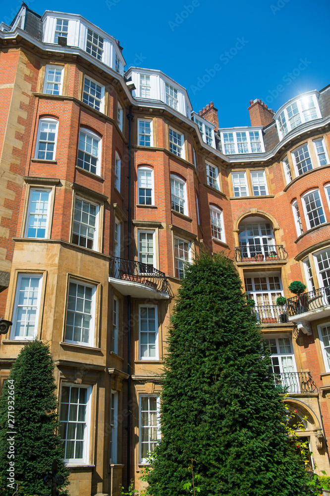 Bright scenic view of traditional red brick architecture in a posh London, England neighborhood under bright blue sky