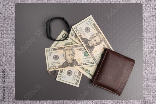 Dollar bills on gray background. Men's leather wallet with dollar bills. Electronic clock on the money. Wedding ring on the dollars. photo