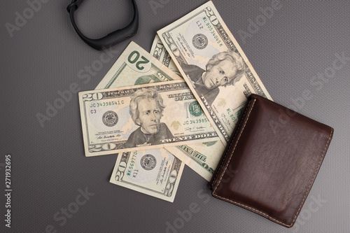 Dollar bills on gray background. Men's leather wallet with dollar bills. Electronic clock on the money.