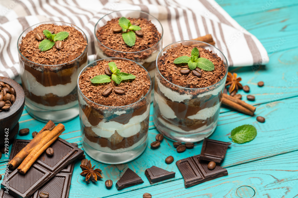 Classic tiramisu dessert in a glass on blue wooden background Classic tiramisu dessert in a glass on blue wooden background