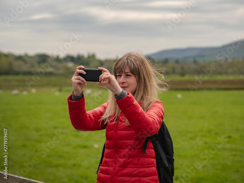 Young woman takes photos of the typical green landscape in Ireland - travel photography
