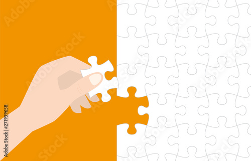 Hand holding last piece jigsaw puzzle on orange background