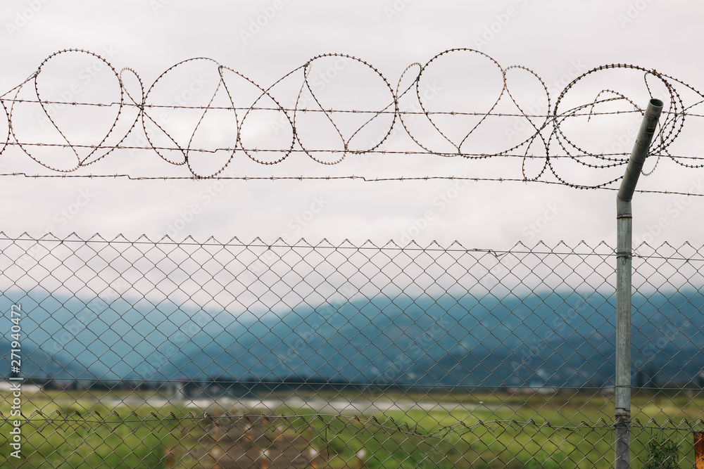 barbed wire fencing against mountains and sky background barbed wire fencing against mountains and sky background