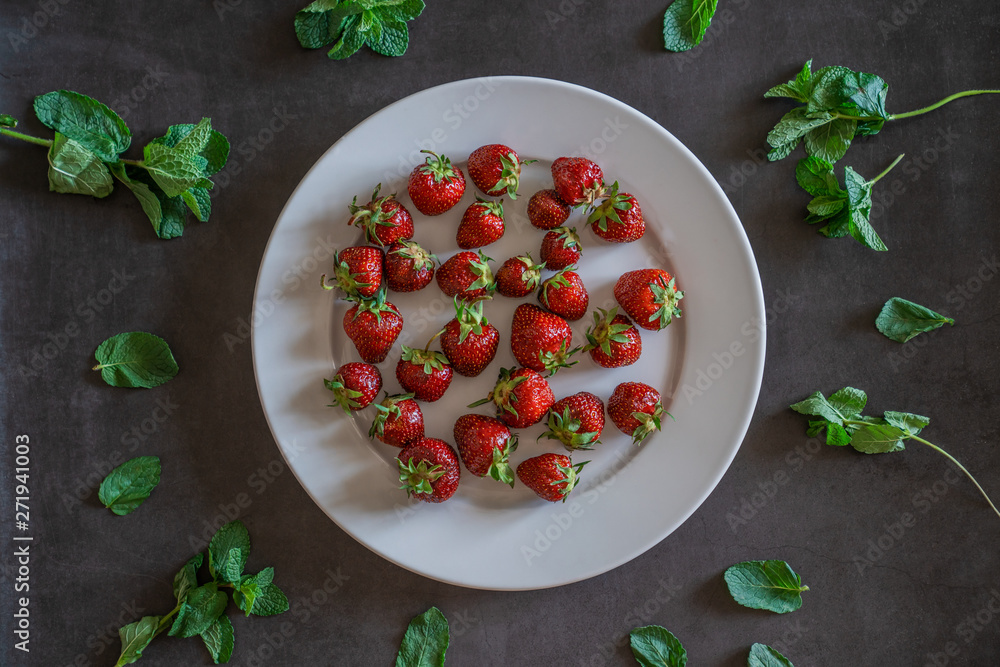 White strawberries dish on dark grey background decorated with sprigs of mint White strawberries dish on dark grey background decorated with sprigs of mint