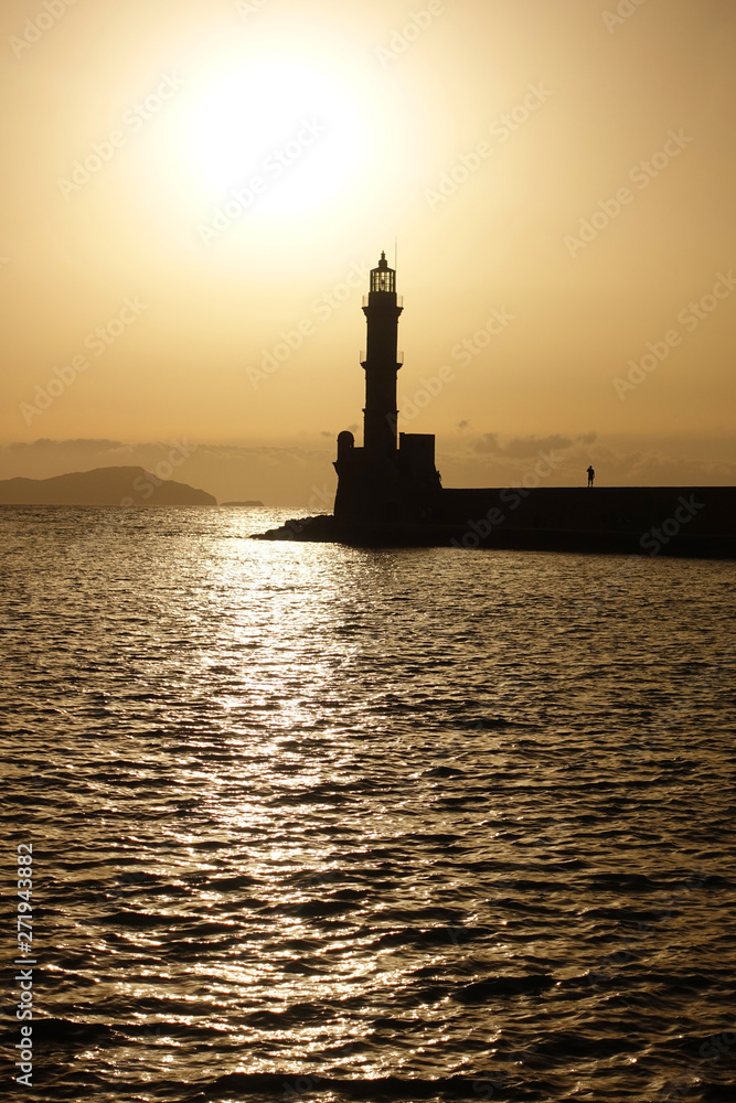 Photo of iconic Venetian lighthouse in old port of Chania at sunset with golden colours, Crete island, Greece