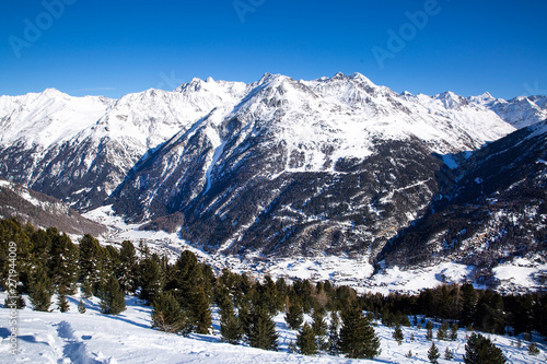 Beautiful Alps in winter and ski village in the valley. Sunny winter day in Tirol, Austria. Ski season. 
