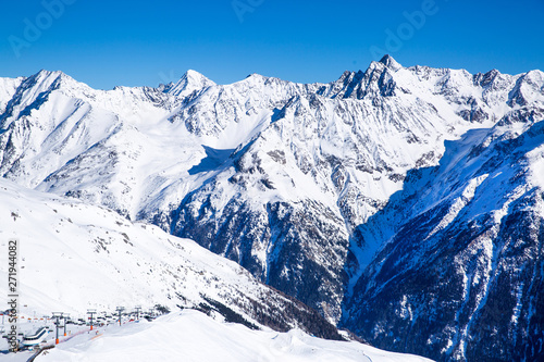 Ski resort in Solden, Tirol, Austria. Beautiful rocky mountains, village in the valley and cable cars. Sunny winter day. 