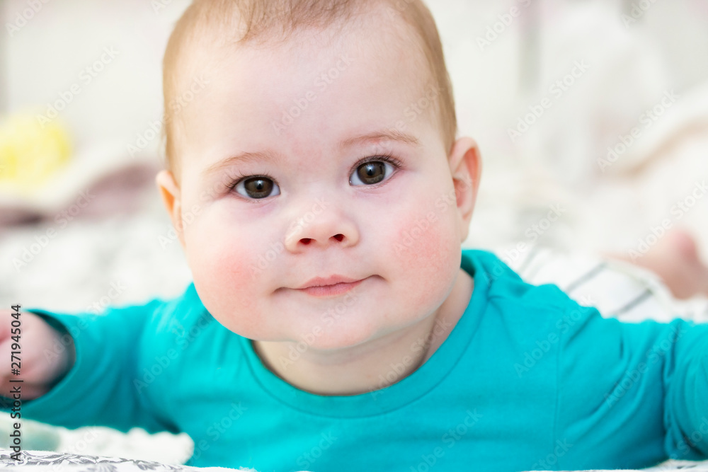 Portrait of a 7 month baby in blue t-shirt, close-up face portrait. Little cute kid looks into camera, good mood positive curiosity Portrait of a 7 month baby in blue t-shirt, close-up face portrait. Little cute kid looks into camera, good mood positive curiosity