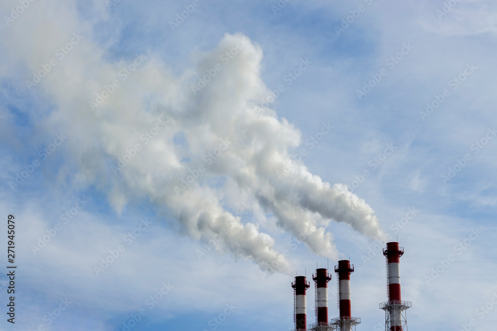 The red-white pipes of the boiler room release white steam into the blue sky. Pipes boiler for heating of multi-storey residential buildings