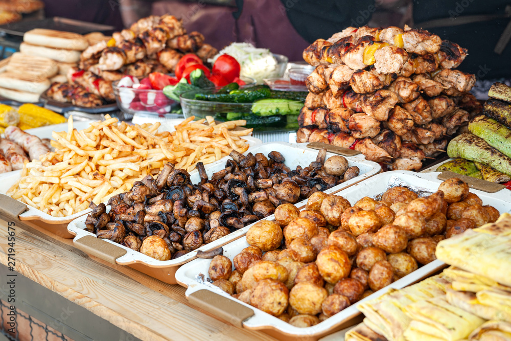 Obraz premium Street food. A lot of grilled meat, grilled mushrooms and grilled vegetables on the window of a street diner.