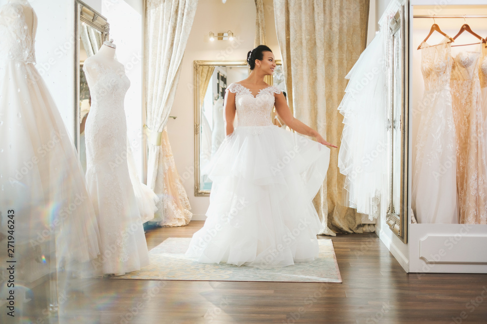 Fototapeta premium Beautifu bride choosing wedding dress in a wedding salon