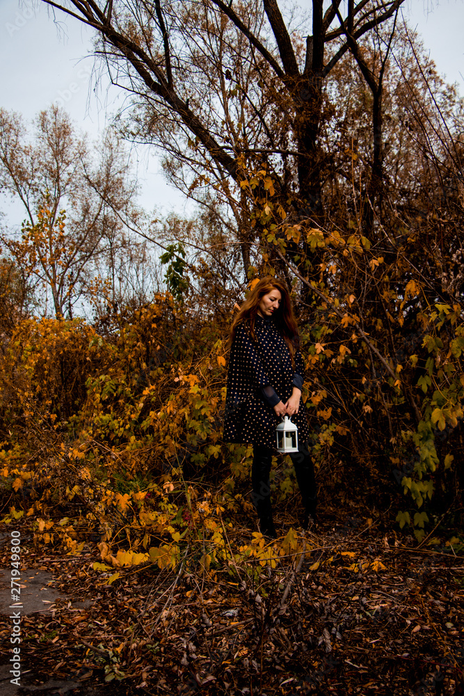 young redhead woman with white lamp in the hand in autumn park