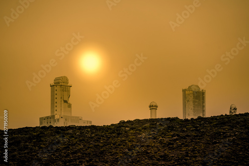 View of a beautiful sunset over  isolated modern buildings. Golden hour on a surreal skyline Modern structures and desert lunar landscape with black rocks..Post-modern architectural futuristic concept
