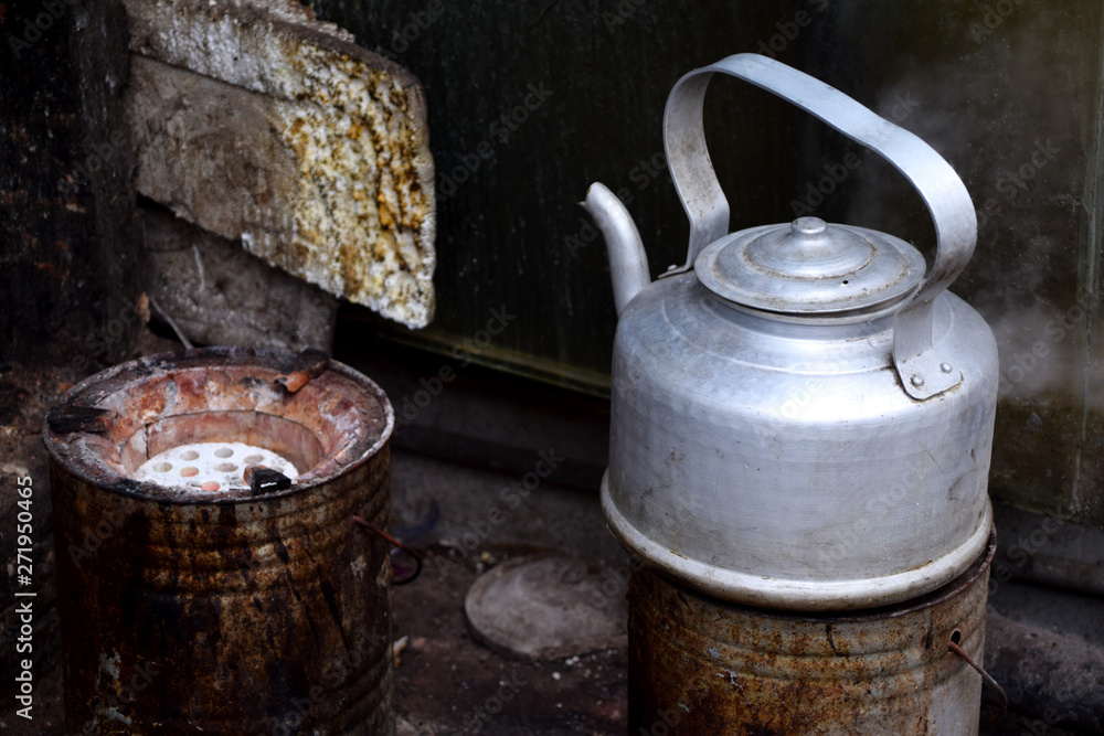 Boiling tea pot on simple stove outdoors in a street food kitchen with the other stove being empty Boiling tea pot on simple stove outdoors in a street food kitchen with the other stove being empty