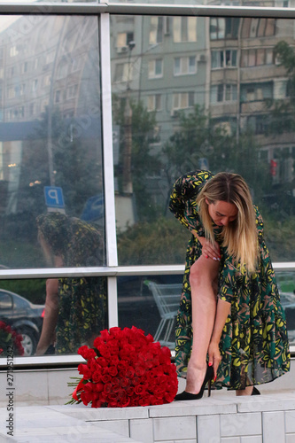 girl in a green dress with a bouquet of red roses at the mirror wall