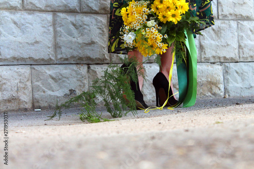 a girl in a green dress with a bouquet of yellow flowers at the concrete wall