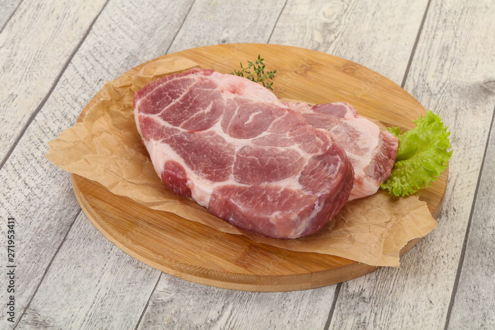Raw pork steak over wooden board Raw pork steak over wooden board