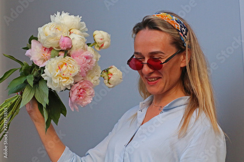 Girl in a blue dress and sneakers with a bouquet of peonies