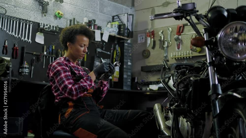 African american woman mechanic repairing a motorcycle in a workshop African american woman mechanic repairing a motorcycle in a workshop