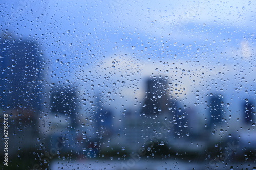 office window covered with rain water. water spray on window. after rain traffic, worker stuck in the office concepts. blur urban skyline background. rainy season concepts.