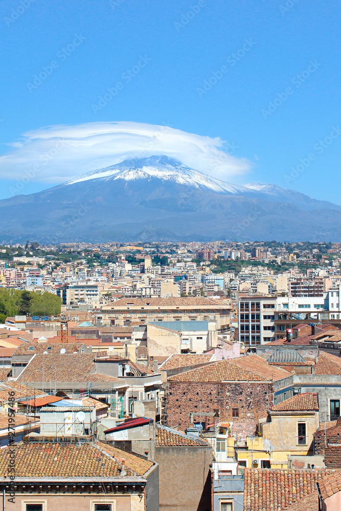Vertical picture capturing famous Mount Etna overlooking the Sicilian city Catania, Italy. Smoke cloud over the famous volcano, snow on the top. The beautiful city is a popular tourist destination