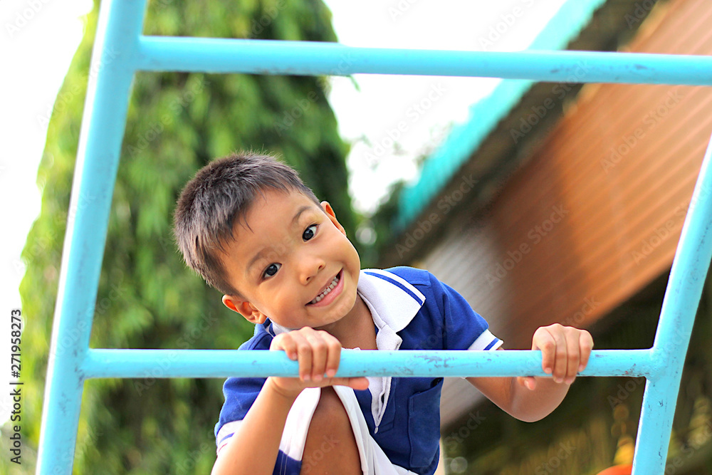 Fototapeta premium Happy asian child boy playing and climbing a steel bar toy at the playground. Kid and sport concept.