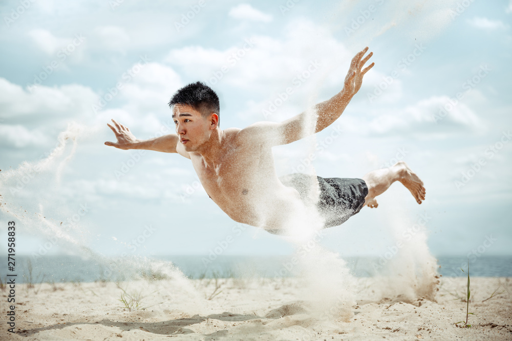 Weightless. Young healthy man athlete doing exercise at the beach. Signle male model shirtless training air at the river side in sunny day. Concept of healthy lifestyle, sport, fitness, bodybuilding. Weightless. Young healthy man athlete doing exercise at the beach. Signle male model shirtless training air at the river side in sunny day. Concept of healthy lifestyle, sport, fitness, bodybuilding.