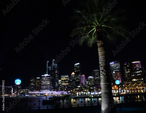 Sydney, Australia - May 27, 2019. Circular Quay illuminated with colourful light design imagery during the Vivid Sydney 2019 free annual public event. Palm tree in the front.