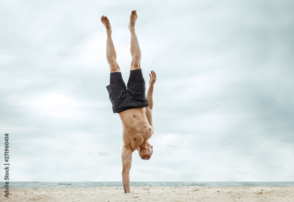Young healthy man athlete doing exercise at the beach. Signle male model shirtless training air at the river side in sunny day. Concept of healthy lifestyle, sport, fitness, bodybuilding.