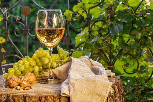 Amber wine in the glass. Georgian national wine according to old technology. Beautiful still life with a drink, fruits and decorations in a rustic style. Copy space. Close up and horizontal view.