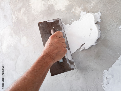 Фотография Builder using plastering tool for finishing old wall.