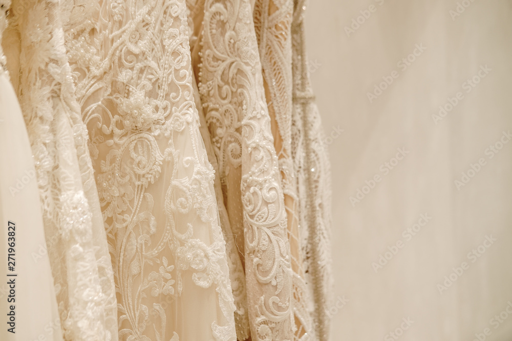 Cream wedding dresses hanging on the hanger in the fitting room. Bridal fashion concept. Champagne, ivory color. Copyspace
