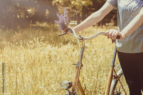 Female hands on handlebars of vintage bicycle in nature. Spring or summer season concept.