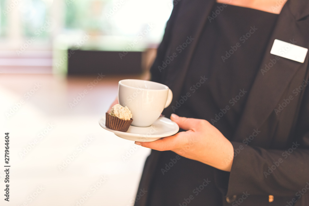 Waitress in uniform holding cup of coffee in cafe.