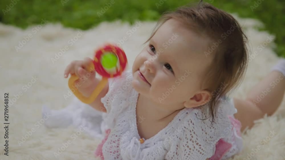 A very small and beautiful girl playing on the bedspread in the park. A very small and beautiful girl playing on the bedspread in the park.