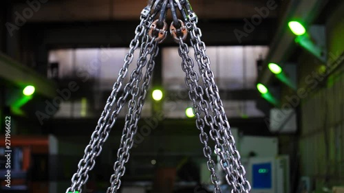 Close up crane hook lifts up metal chains. Work in a warehouse of metal, transportation of metal products. Gantry crane is unloading a container