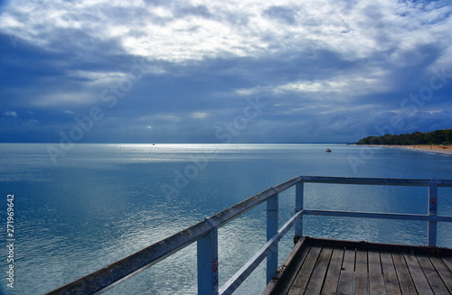 Gushing sea on a cloudy day. Horizontal view of dramatic overcast sky and sea. Fifty shades of blue and gray. View from a wooden pier.