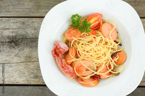 pasta spaghetti with fried sausage in white plate on wood table background.